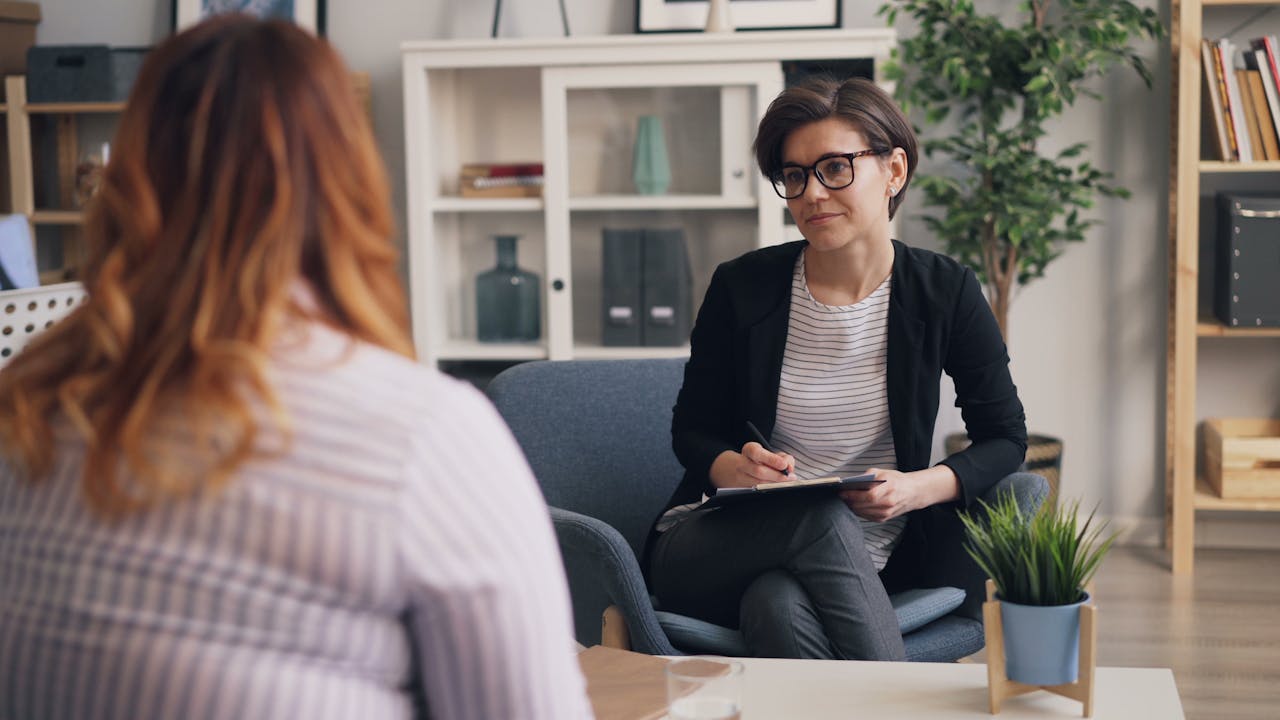 A therapist and patient having a counseling session in a modern office sitting area.